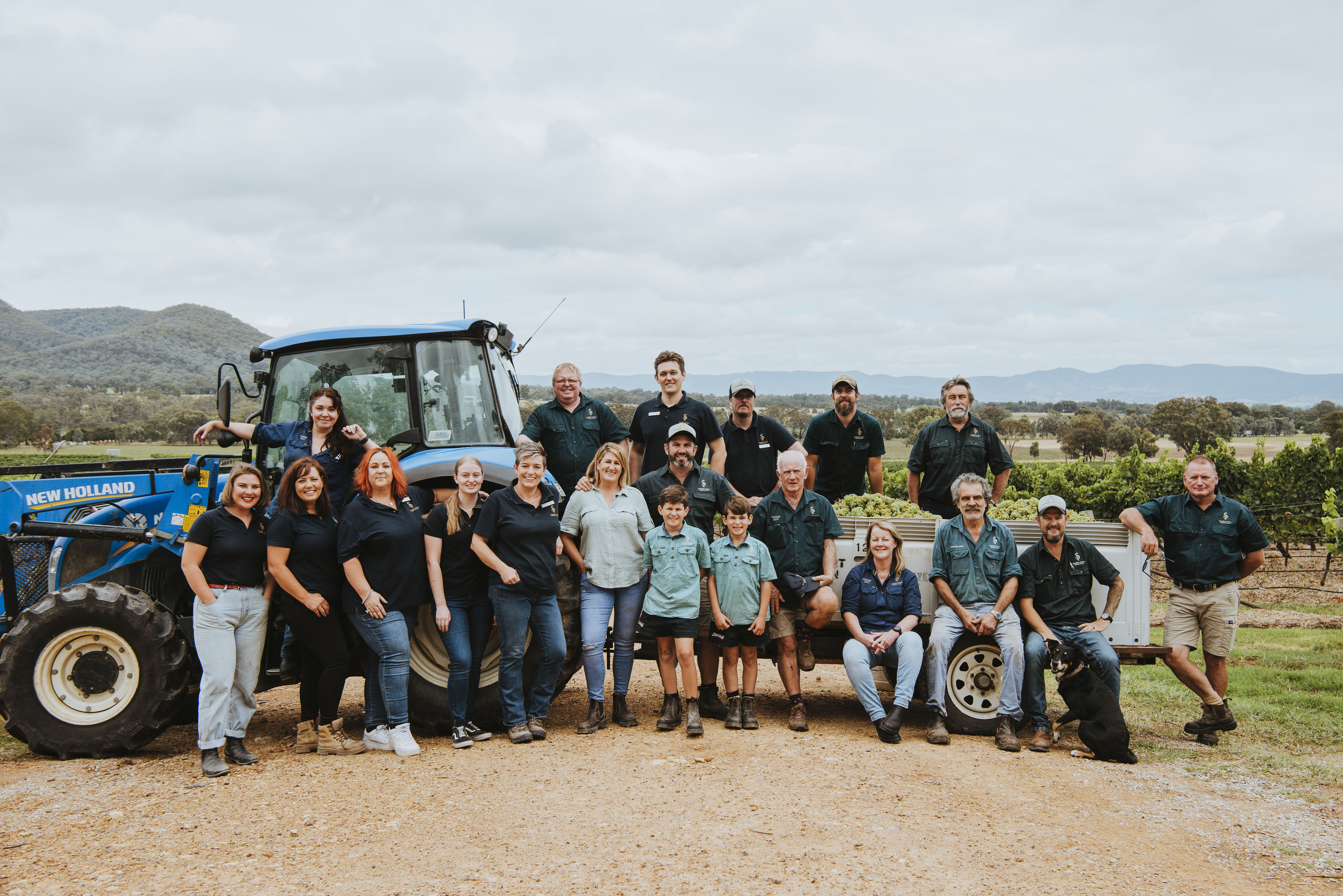 People posing in front of the tractor in the vineyard